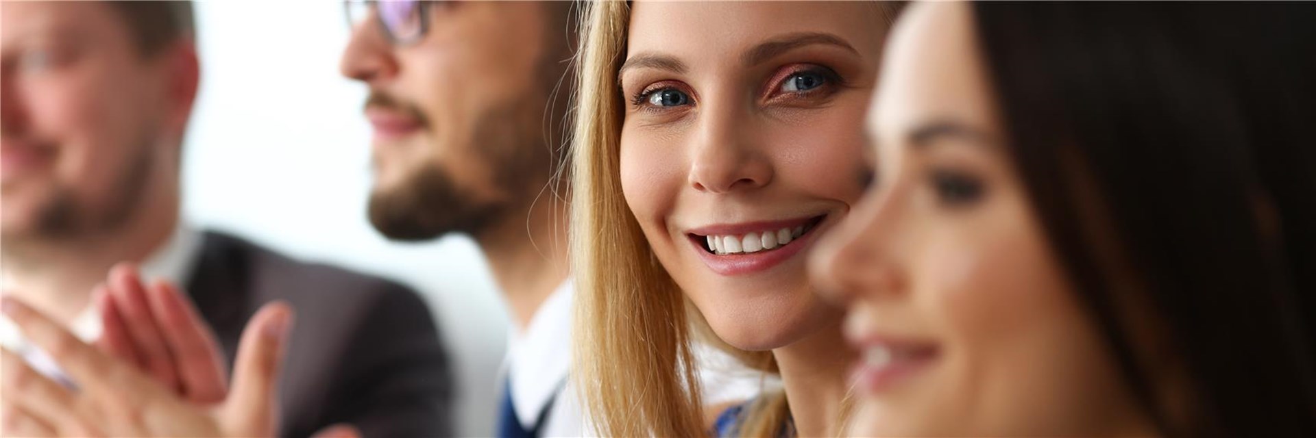 Junge Frau sitzt neben anderen und lächelt